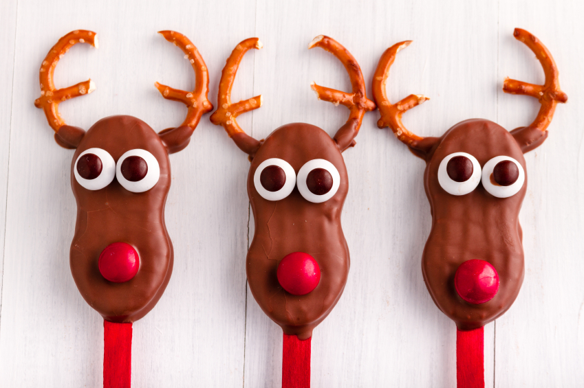 Line of holiday reindeer cake pops on white wooden table