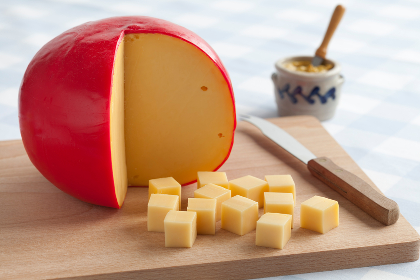 Edam cheese and cubes on a cutting board